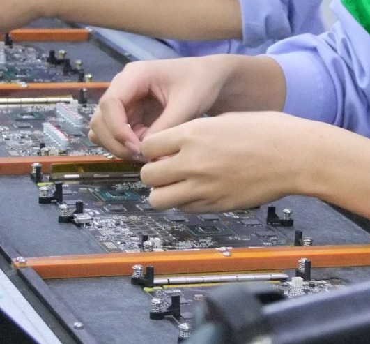 Picture of a worker manualy instaling components onto the board